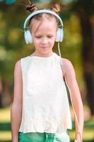 kleines entzückendes mädchen, das musik im park hört foto