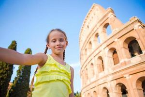 kleines mädchen, das selfie hintergrund macht kolosseum, rom, italien. Kinderporträt an berühmten Orten in Europa foto