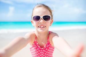 glückliches kleines mädchen, das selfie am tropischen strand auf exotischer insel macht foto