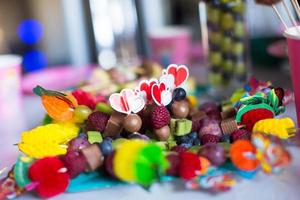 Canape aus Obst, weiße Schokoladenkuchen und Popcorn auf dem süßen Kindertisch bei der Geburtstagsfeier foto