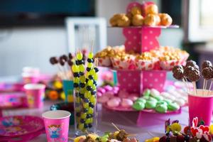 Canape aus Obst, weiße Schokoladenkuchen und Popcorn auf dem süßen Kindertisch bei der Geburtstagsfeier foto