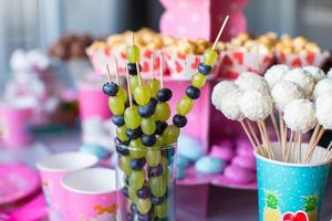 Canape aus Obst, weiße Schokoladenkuchen und Popcorn auf dem süßen Kindertisch bei der Geburtstagsfeier foto