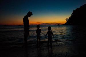 vater und töchter silhouetten im sonnenuntergang am strand auf boracay, philippinen foto