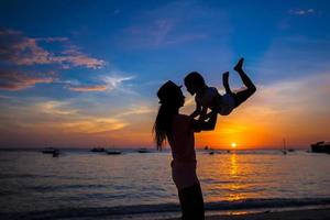 Kleines Mädchen und ihre Mutter amüsieren sich bei Sonnenuntergang auf der Insel Boracay, Philippinen foto