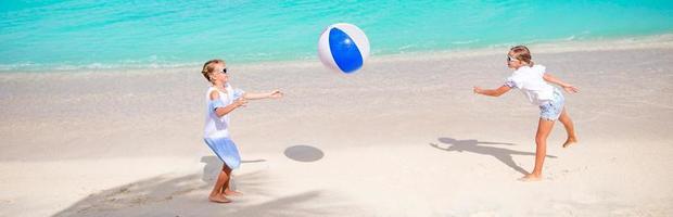 kleine entzückende mädchen, die am strand mit luftball spielen foto