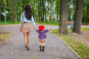 junge Mutter, die mit ihrer kleinen Tochter im Herbstpark geht