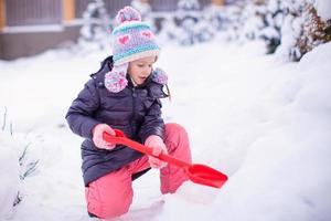 kleines Mädchen spielt mit roter Schaufel im Garten foto