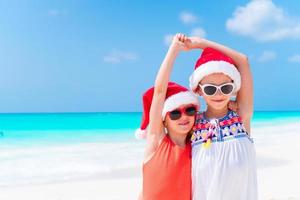 entzückende kleine kinder in weihnachtsmütze während der weihnachtsstrandferien. Silvester am Strand foto