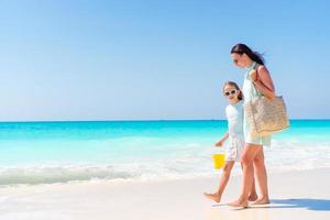 kleines entzückendes Mädchen und junge Mutter am tropischen Strand
