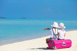 kleine Mädchen mit großem Koffer und Karte am tropischen Strand foto