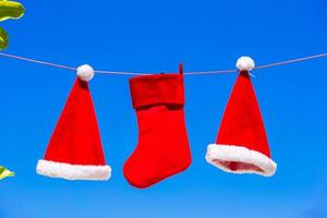 Rote Weihnachtsmützen und Weihnachtsstrumpf hängen am tropischen Strand foto