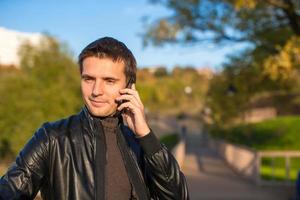 junger Mann mit einem Telefon im Park foto