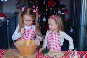 süße kleine mädchen, die lebkuchenplätzchen für weihnachten zubereiten foto