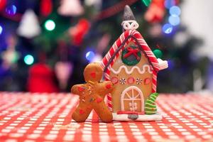 süßer lebkuchenmann vor seinem süßigkeitsingwerhaushintergrund der weihnachtsbaum beleuchtet foto