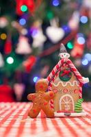 Lebkuchenmann vor seinem Candy Ginger House Hintergrund der Weihnachtsbaum leuchtet foto