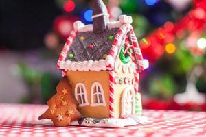 Lebkuchenhaus, dekoriert mit süßen Bonbons auf einem Hintergrund aus hellem Weihnachtsbaum mit Girlande foto