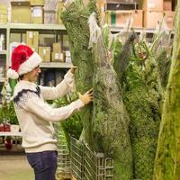 junger mann, der grünen weihnachtsbaum auf dem markt kauft foto