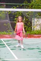 kleines Mädchen, das auf dem Platz Tennis spielt foto