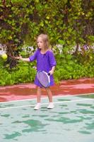 kleines Mädchen, das auf dem Platz Tennis spielt foto