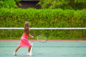 kleines Mädchen, das auf dem Platz Tennis spielt foto