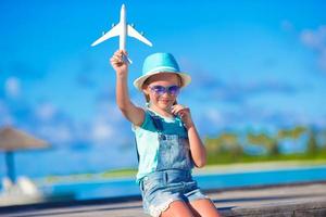 glückliches kleines Mädchen mit Spielzeugflugzeug in den Händen am weißen Sandstrand foto