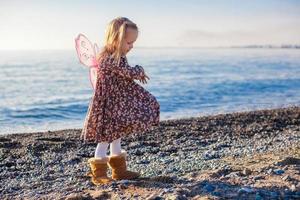 entzückendes kleines Mädchen am Strand an einem sonnigen Wintertag foto