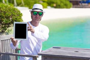 junger mann mit tablet-computer während des tropischen strandurlaubs foto