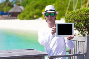 junger mann mit tablet-computer während des tropischen strandurlaubs foto