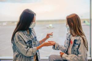 mutter und kleines mädchen mit medizinischen masken am flughafen. Schutz vor Coronavirus und Grip foto