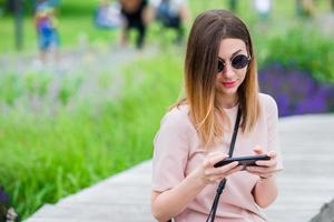 touristenmädchen, das in den sommerferien messgae per smartphone sendet. junge attraktive frau mit handy im freien, das urlaubsreiseziel im tourismus genießt und konzept erkundet foto