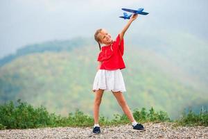 glückliches kleines Mädchen mit Spielzeugflugzeug in den Händen in den Bergen foto