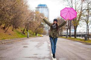 junge frau, die mit regenschirm am regnerischen tag des herbstes geht foto