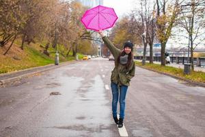 junge frau, die mit regenschirm am regnerischen tag des herbstes geht foto