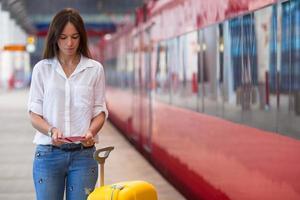 junges kaukasisches Mädchen mit Gepäck am Bahnhof, der mit dem Zug reist foto