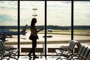 Silhouette von Fluggästen in einer Flughafenlounge, die auf Flugflugzeuge warten foto