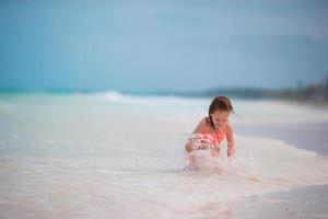 entzückendes kleines mädchen hat spaß am tropischen strand während des urlaubs foto