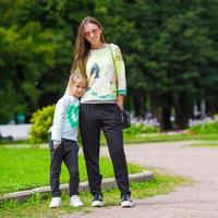 glückliche mutter und entzückendes kleines mädchen, das warmes wetter im schönen park genießt foto