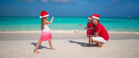 Kleines Mädchen, das am Strand ein Foto ihrer Familie macht