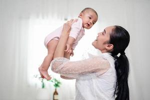 Muttererziehung und neugeborenes Geburtsleben. mutter und baby spielen im sonnigen schlafzimmer, familie hat spaß zusammen. kinderbetreuung, mutterschaftskonzept. foto