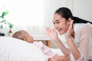 Muttererziehung und neugeborenes Geburtsleben. mutter und baby spielen im sonnigen schlafzimmer, familie hat spaß zusammen. kinderbetreuung, mutterschaftskonzept. foto