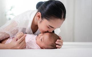 Muttererziehung und neugeborenes Geburtsleben. mutter und baby spielen im sonnigen schlafzimmer, familie hat spaß zusammen. kinderbetreuung, mutterschaftskonzept. foto