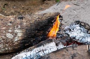 Verfallende Kohlen und brennende Kohlen zum Kochen, hell brennende Holzstämme mit gelben, heißen Feuerflammen. foto