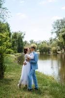 Braut in einem leichten Hochzeitskleid zum Bräutigam in einem blauen Anzug foto