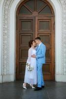 Braut in einem leichten Hochzeitskleid zum Bräutigam in einem blauen Anzug foto