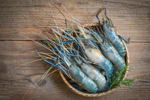 rohe Garnelen auf hölzernem Hintergrund der Platte zum Kochen von Speisen, frische Garnelen, Meeresfrüchte mit Rosmarin foto