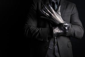 Porträt eines starken Mannes im dunklen Anzug, der schwarze Lederhandschuhe anzieht. dunkle kriminelle Aktivitäten. Androhung gefährlicher Gewalt foto