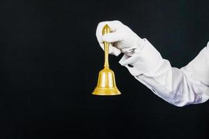 Nahaufnahme isoliertes Bild des Arms mit goldener Glocke. kopierraum für die dienstleistungsbranche und professionelle gastronomie. zum Service klingeln. foto