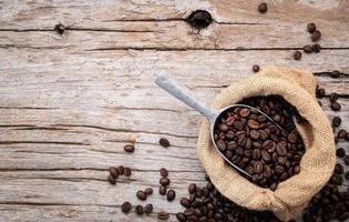 Hintergrund dunkel gerösteter Kaffeebohnen mit Schaufeln auf Holzhintergrund mit Kopierraum. foto