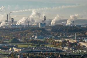 Panoramablick auf den Rauch von Rohren als Hintergrund eines riesigen Wohnkomplexes mit Hochhäusern und privatem Sektor. Konzept der Luft- und Wasserverschmutzung foto