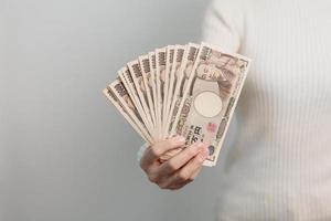 Frauenhand, die Banknotenstapel des japanischen Yen hält. Tausend Yen Geld. japanische bargeld-, steuer-, rezessionswirtschafts-, inflations-, investitions-, finanz- und einkaufszahlungskonzepte foto